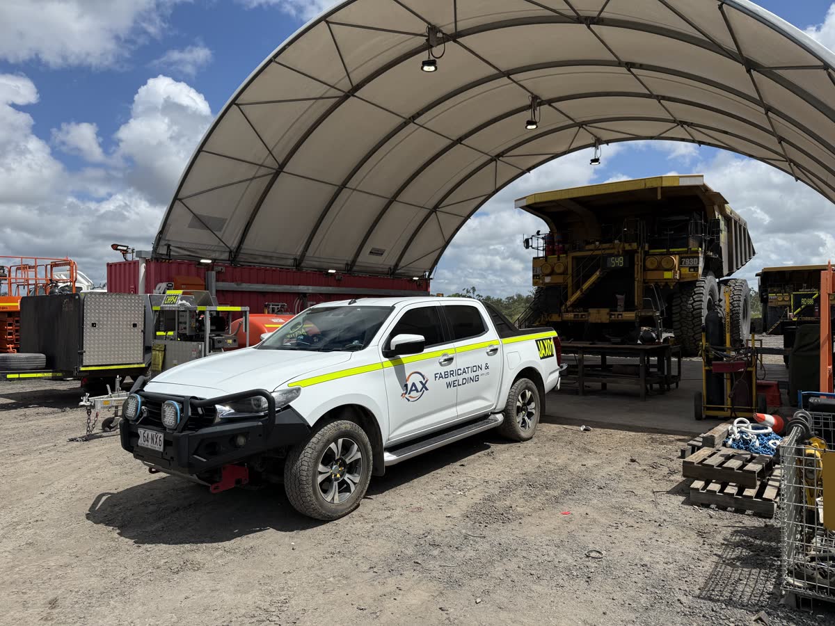 JAX Fabrication service vehicle at a mine site maintenance bay with CAT 793D haul truck under repair